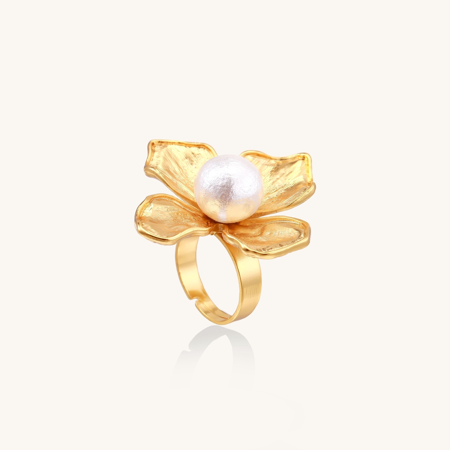 Gold-plated brass ring with dimensional 5-petal flower design and white cotton pearl center on neutral background.