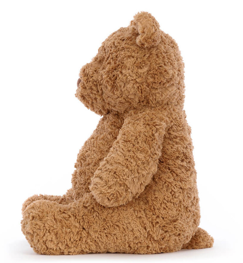 Sideview Bartholomew Bear brown teddy bear sitting on a white background