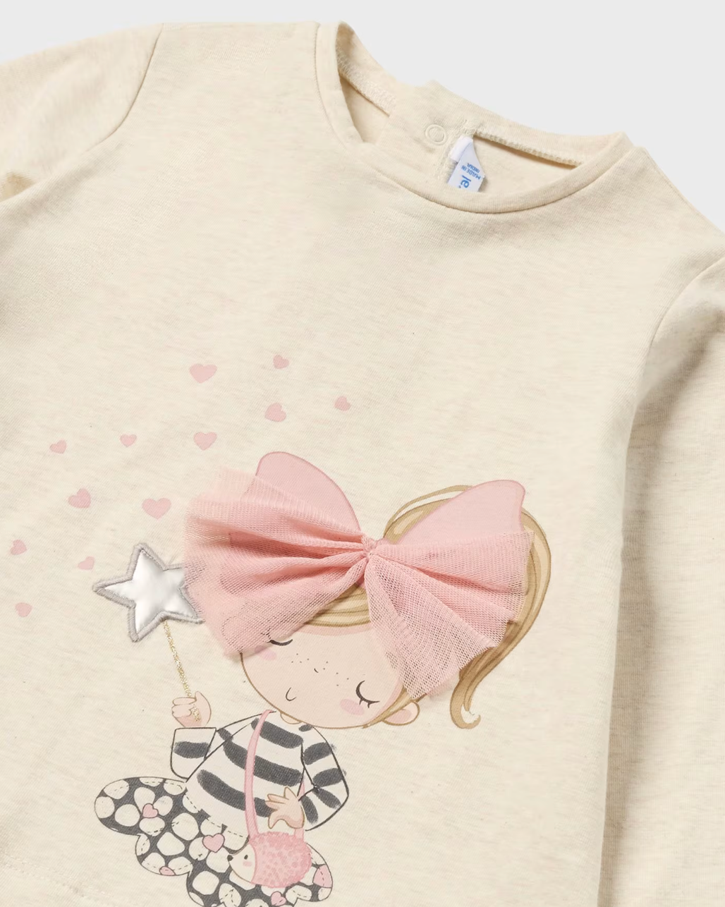 Close up of beige and pink long sleeve t-shirt with pink bow.