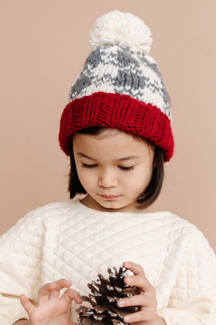 Little girl wearing a Blueberry Hill buffalo check beanie in cream, gray, and red colors.