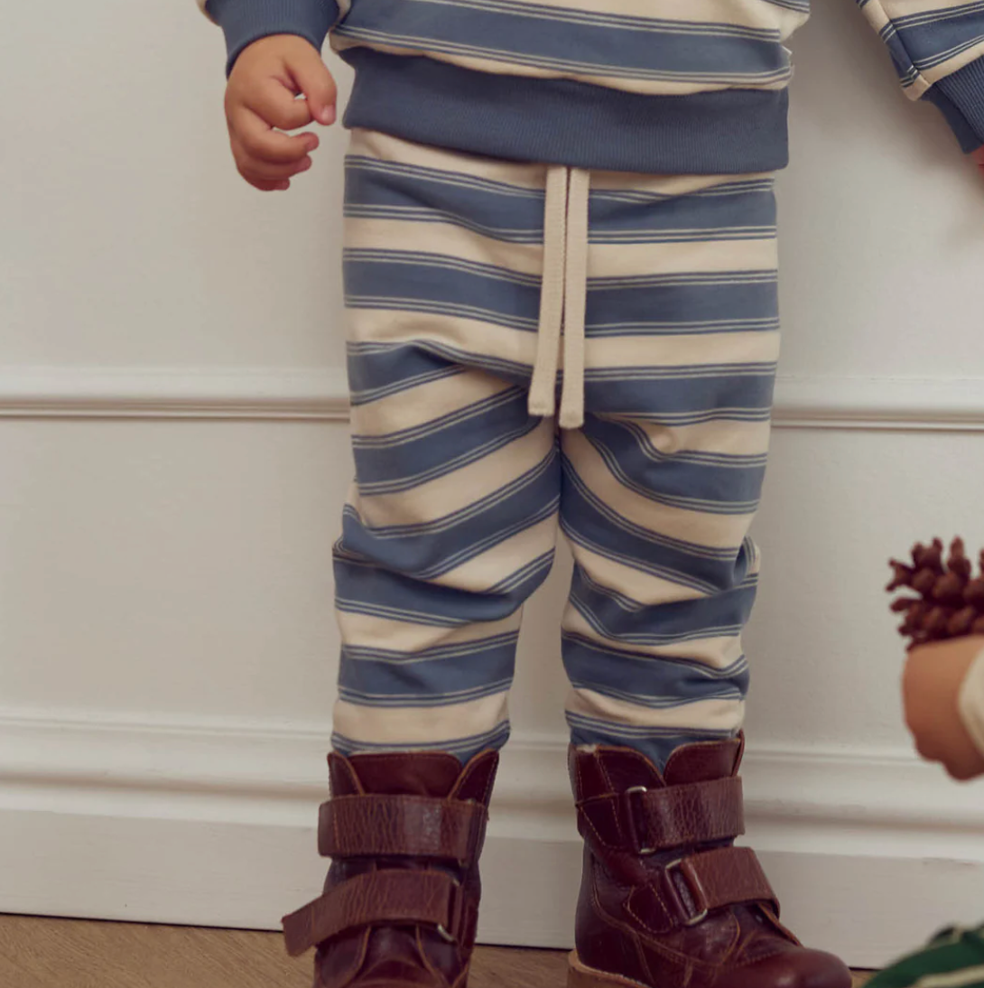 Child wearing Green Cotton Group blue and white striped pants with brown boots on a neutral background