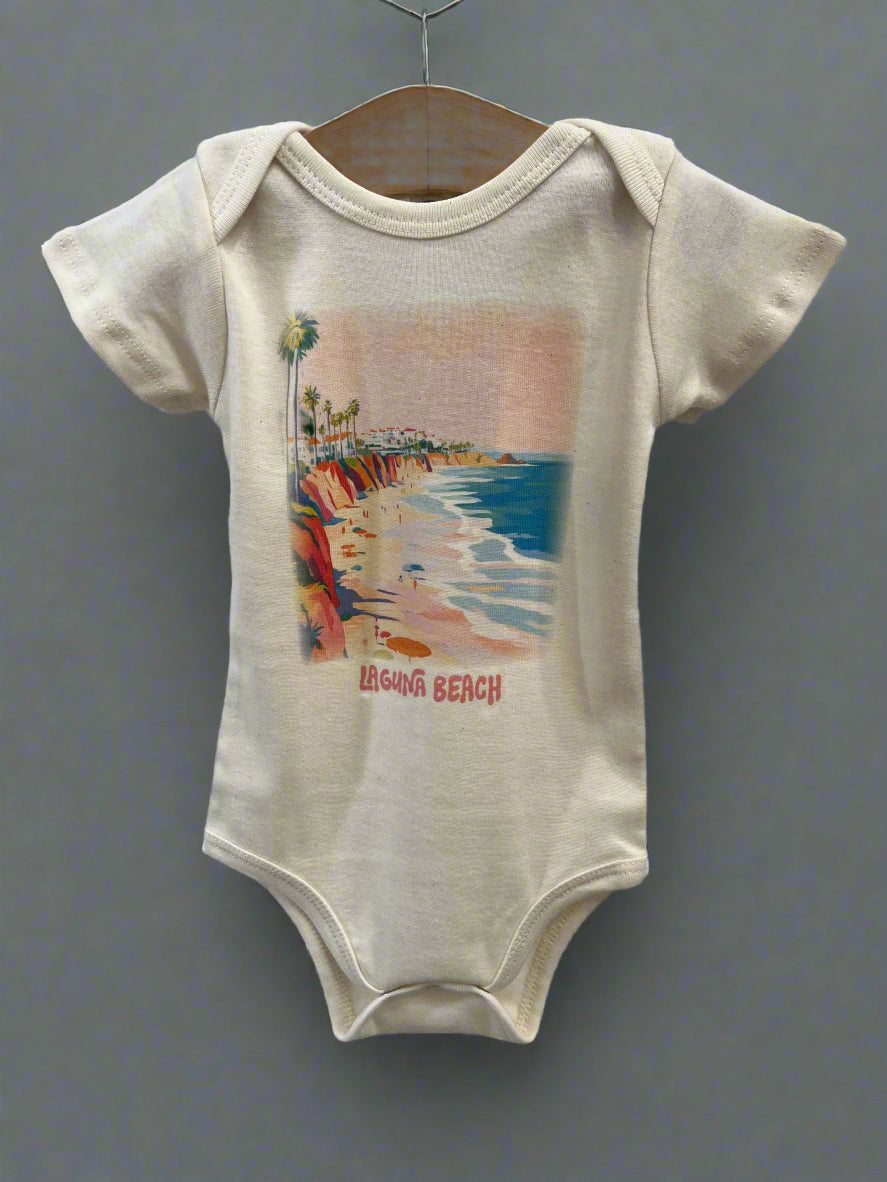A white short-sleeved onesie with a watercolor print of a beach scene, labeled 'Laguna Beach'.