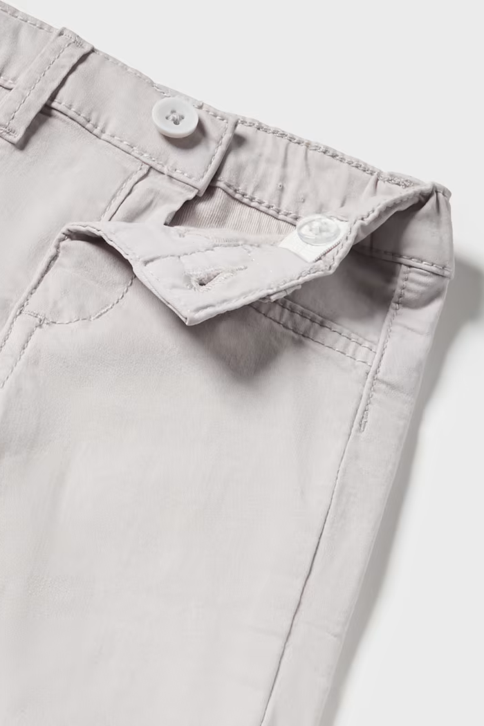 A pair of beige cotton dress pants with an adjustable elastic waistband and a button-up front.