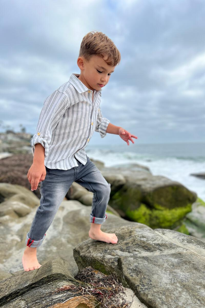 Little boy wearing Me & henry dark grey jeans on the rocks at the beach