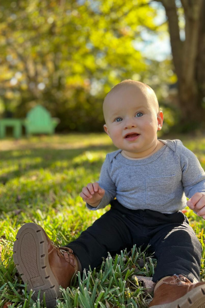 A little boy wearing Me & Henry Jonathan pant sitting in the grass