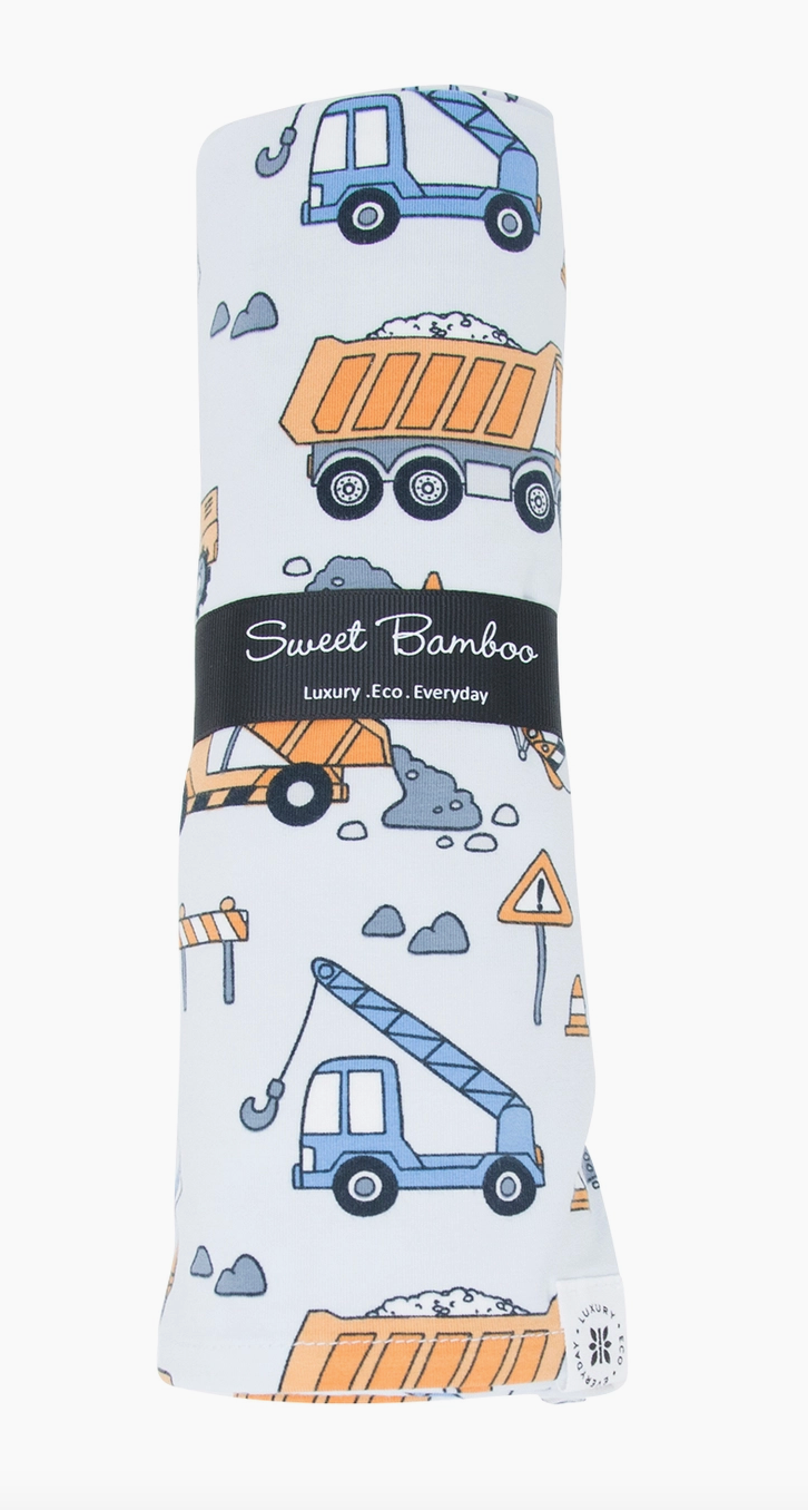 Bamboo receiving blanket with construction vehicles design, rolled up with branding tag visible.