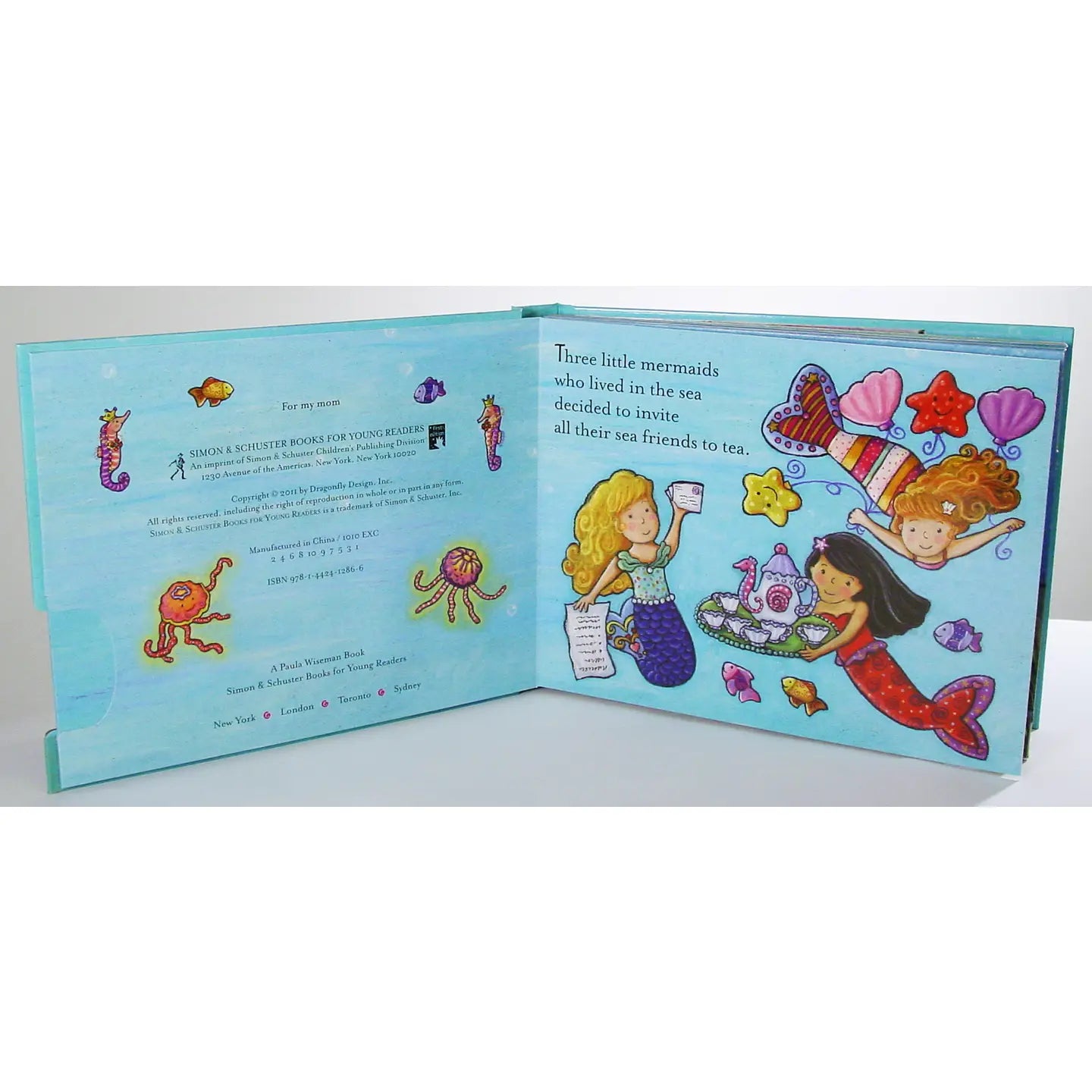 Open book with mermaid illustrations and text on a white background