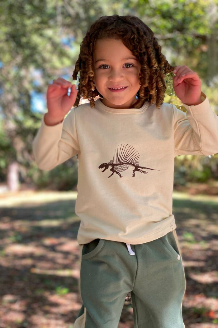 Young boy wearing a Me and Henry beige dinosaur sweater
