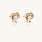 Gold-plated flower stud earrings with freshwater pearl centers on beige background, showing textured petal details.