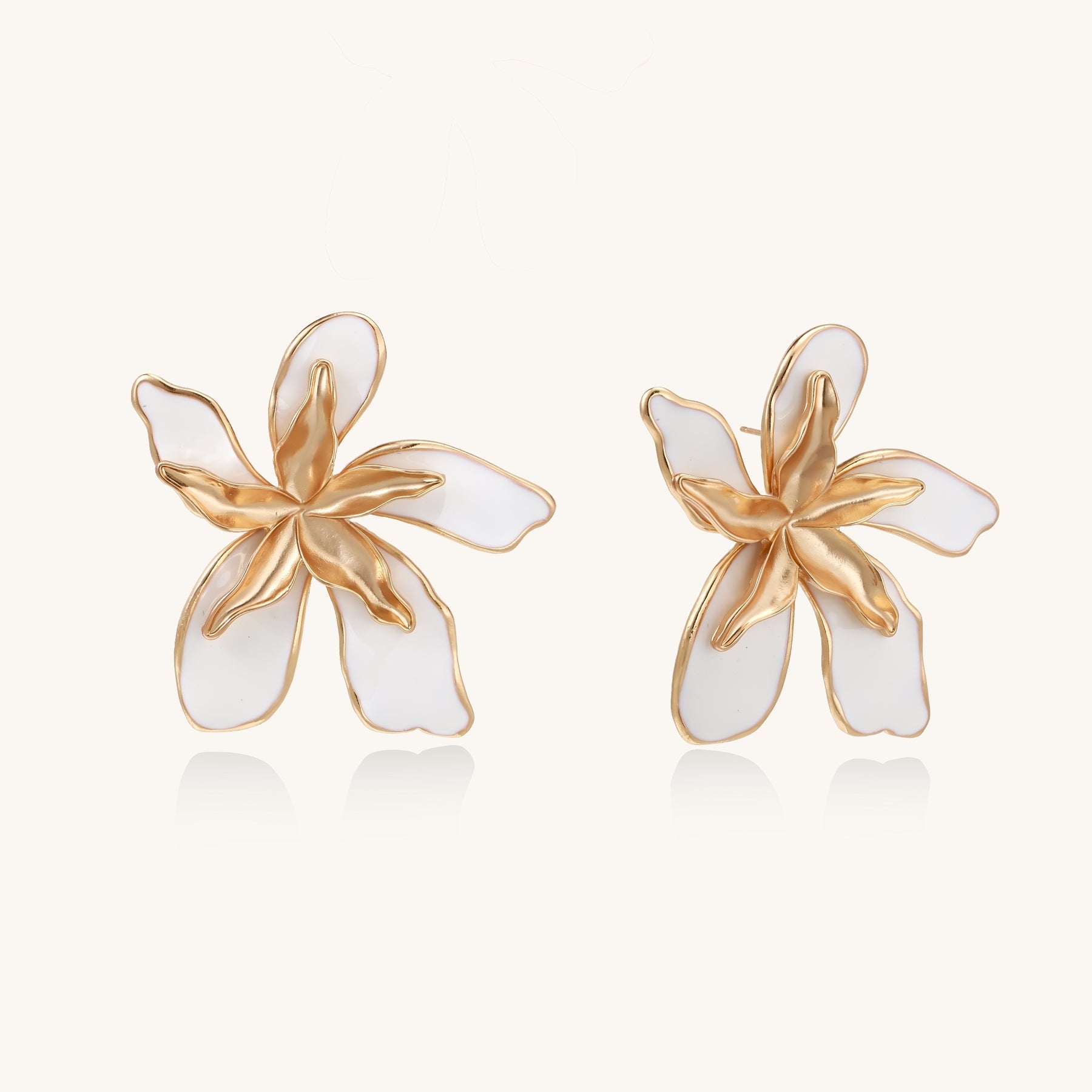 Large floral stud earrings with gold-plated brass petals and white enamel centers on neutral background