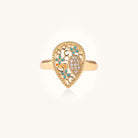 Gold-plated heart ring with turquoise enamel scrollwork and cubic zirconia stones on white background