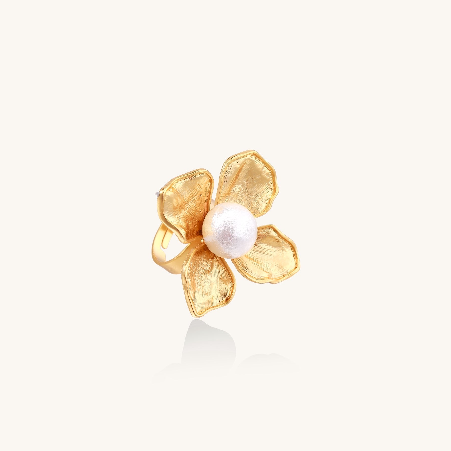 Gold-plated brass ring with dimensional 5-petal flower design and white cotton pearl center on neutral background.