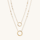 Gold-plated layered necklace set with two circular pendants featuring white centers on delicate chains.
