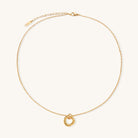 Close-up of a gold-plated stainless steel necklace with interlocking twisted ring pendant on white background