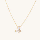 Delicate gold butterfly necklace with white mother of pearl wings on fine chain, displayed on neutral background.