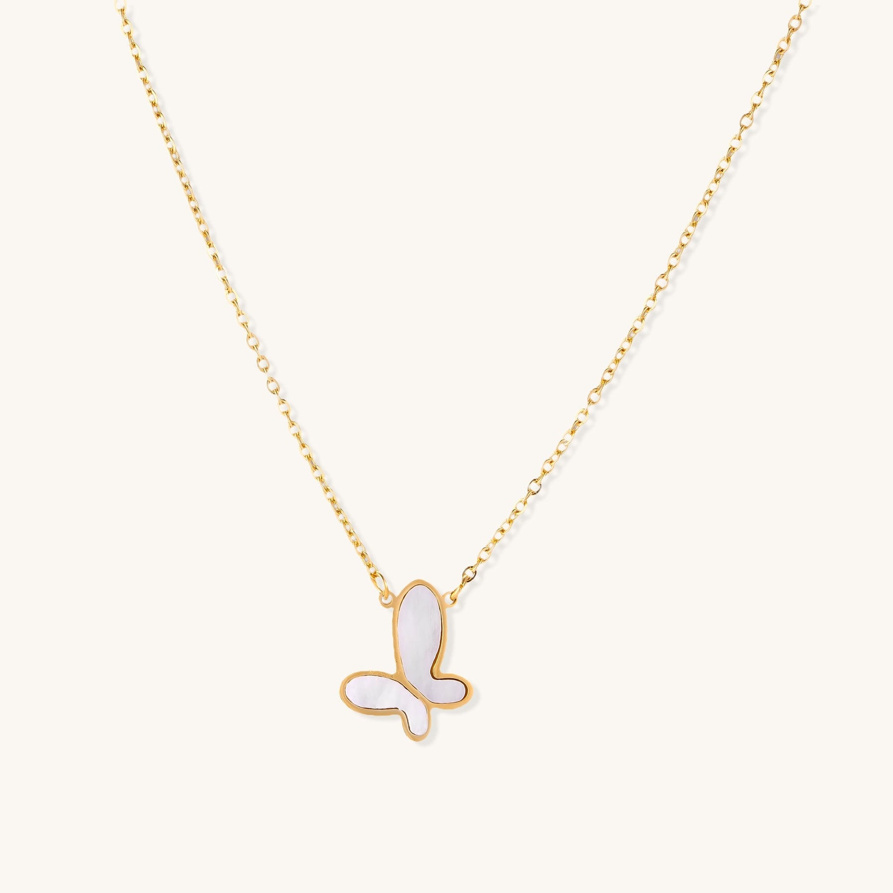 Delicate gold butterfly necklace with white mother of pearl wings on fine chain, displayed on neutral background.