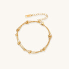 Delicate 18K gold plated bracelet with spherical beads on layered chains and adjustable extender on white background