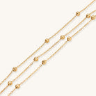 Delicate 18K gold plated bracelet with spherical beads on layered chains and adjustable extender on white background