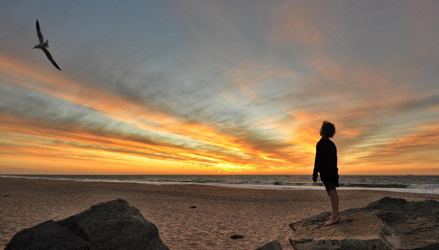 Young boy on the beach at sun set