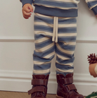 Child wearing Green Cotton Group blue and white striped pants with brown boots on a neutral background