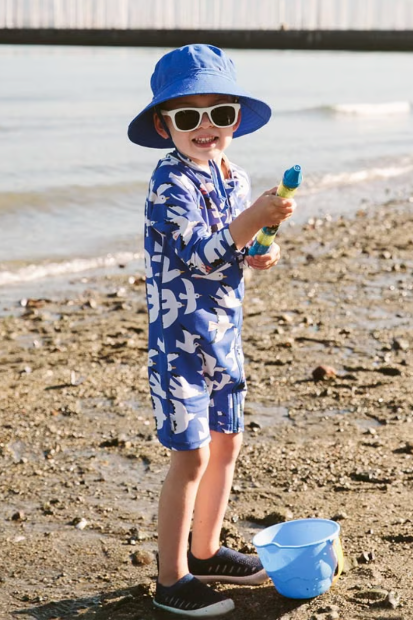 A boy at the beach wearing a Jan and Jul bucket hat