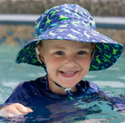 A boy in the water wearing a Jan & Jul dino printed bucket hat