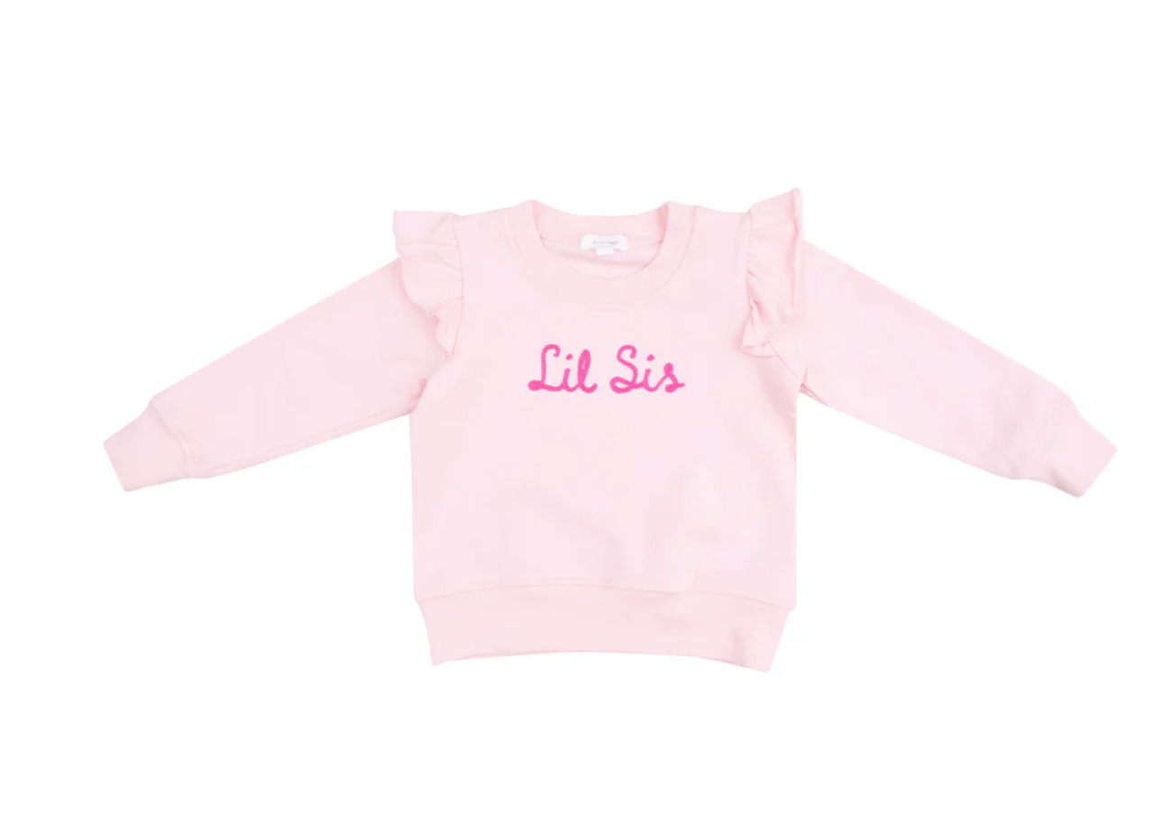 A pink ruffle shoulder sweatshirt with 'Lil Sis' embroidered on the front in pink letters.