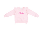 A pink ruffle shoulder sweatshirt with 'Lil Sis' embroidered on the front in pink letters.
