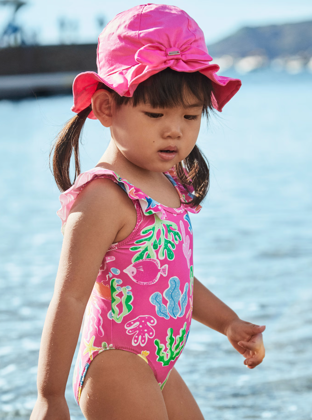 Little girl wearing mayoral pink swim set with hat