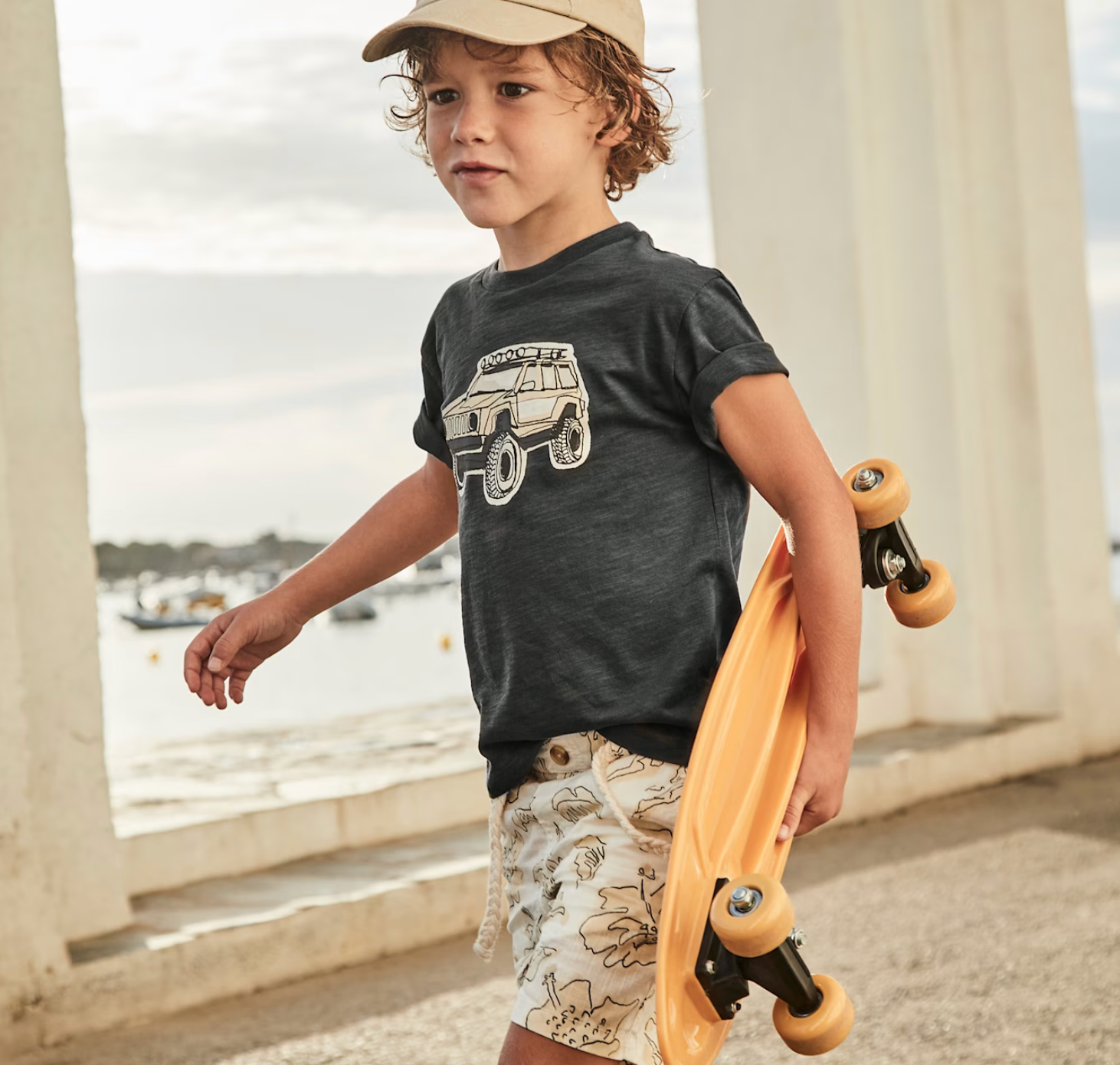 Boy wearing off road t-shirt carrying a skateboard