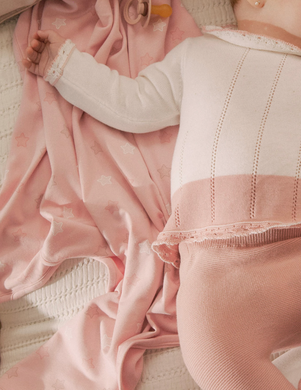 Baby girl laying on a pink star printed swaddle blanket