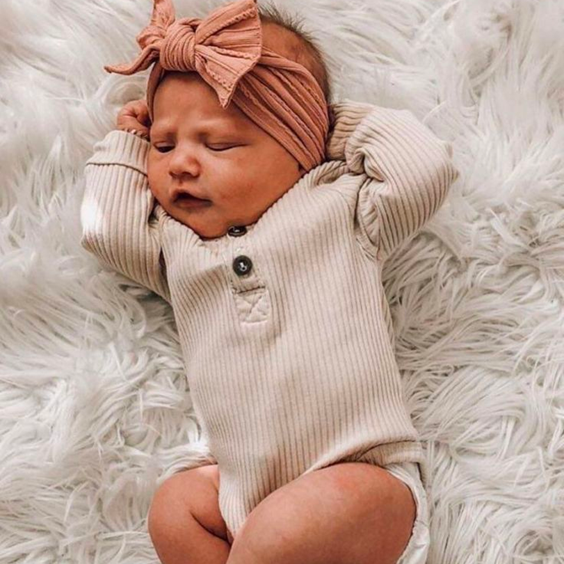 newborn baby laying on a blanket in baby clothes.