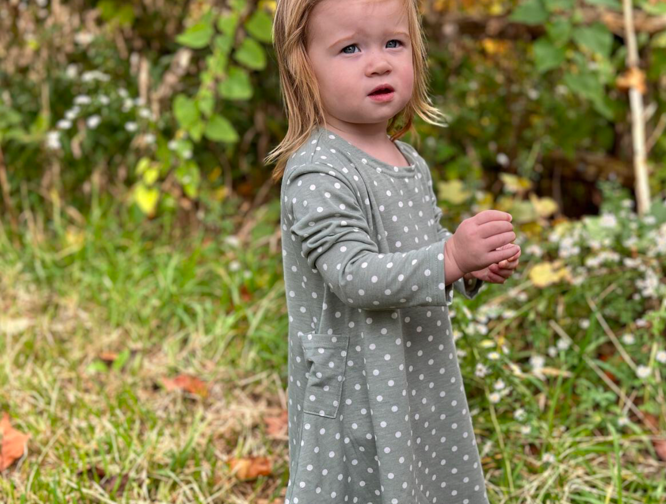 Little girl in Vignette sage green baby dress with white polka dots